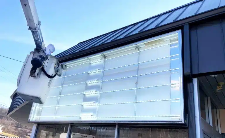 Cabinet-Sign-LED-Retrofit_-Fluorescent-to-LED-Replacement » led strip light Production R&D Manufacturer|NPHIS Technician installing LED lights in outdoor sign for energy-efficient upgrade.