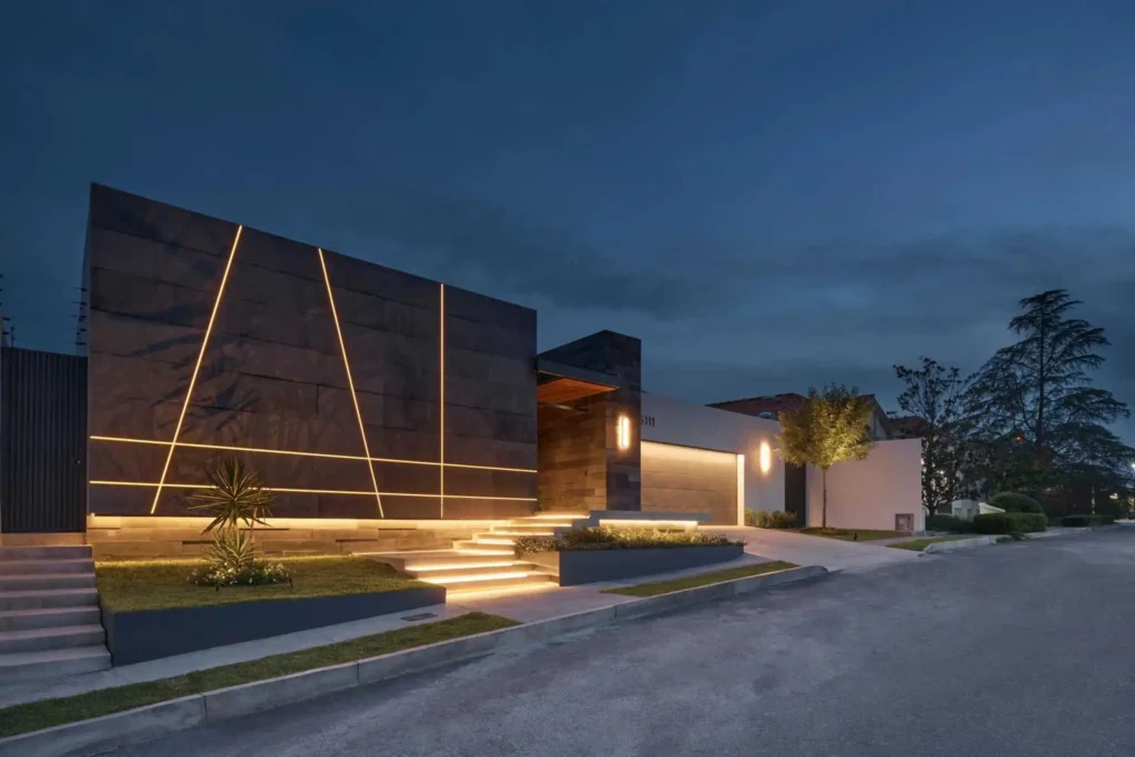 Modern luxury villa exterior featuring seamless linear LED strip lighting on facade and steps at night
