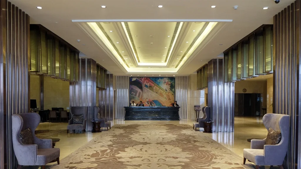 Luxury 5-star hotel lobby featuring warm white LED cove lighting along ceiling and marble columns