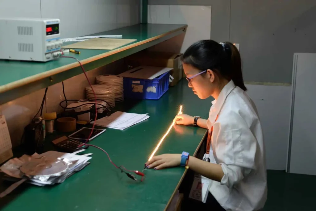 Factory technician performing quality control test on glowing LED light strip in production