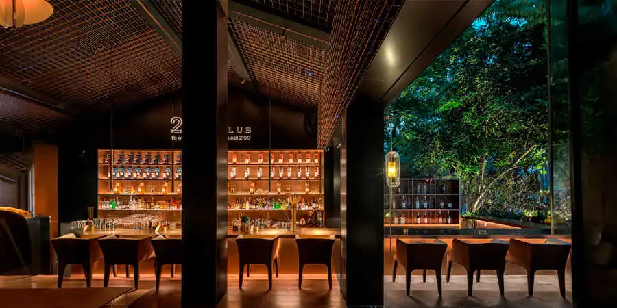 Luxury hotel bar with warm LED strip lighting illuminating liquor shelves and under-counter creating an upscale atmosphere