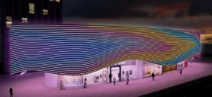 Commercial retail building exterior at night covered in dense parallel wavy lines of multicolor neon LED strip lights in white, cyan, yellow and orange tones, creating a dramatic flowing wave pattern across the entire facade with pedestrians visible below
