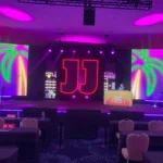 Complete event stage lighting design featuring custom LED signs and RGBW strips managed by DMX lighting controllers.