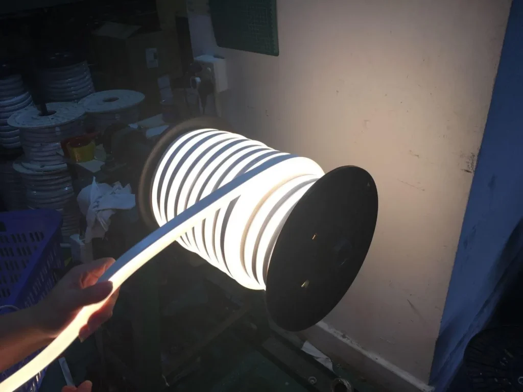NPHIS LED factory worker holding a lit reel of top bend silicone neon flex during production quality inspection — dot-free linear lighting output, wholesale LED neon flex manufacturer China