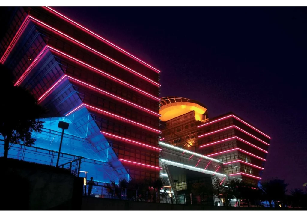 Top bend LED neon flex outlining a large commercial building facade at night — multi-floor architectural contour lighting with red and pink IP67 silicone neon flex for outdoor building outline projects