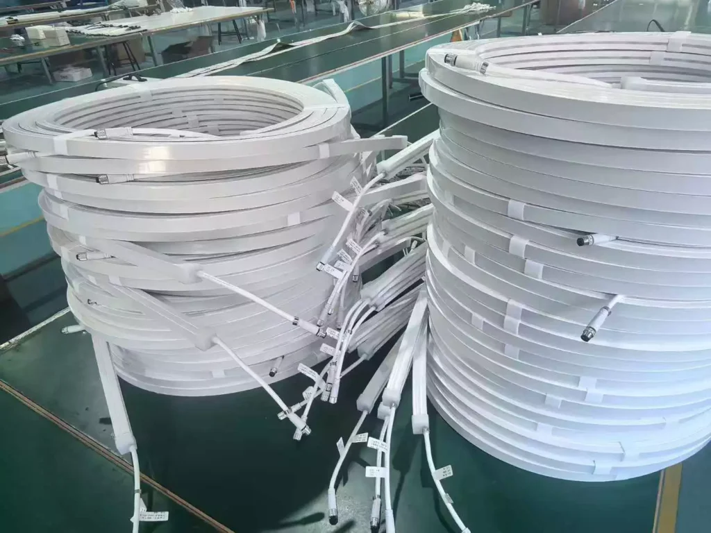 Two coils of white anti-yellowing silicone LED neon flex on a factory workbench, ready for batch quality inspection before wholesale shipment to importers