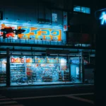 Large outdoor LED neon flex facade signage lighting up a multi-story drugstore building along a city street at night, illustrating durable UV resistant silicone neon flex for facade lighting and commercial building exteriors.